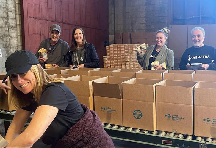 Five individuals pack brown boxes