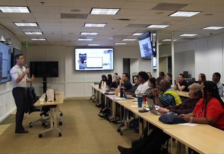 An individual teaches a diverse group of individuals in a conference room.