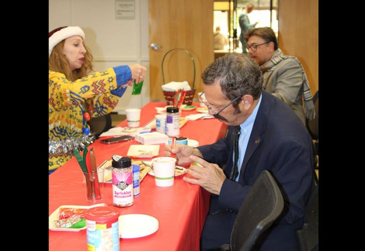 Three individuals decorate cookies. 