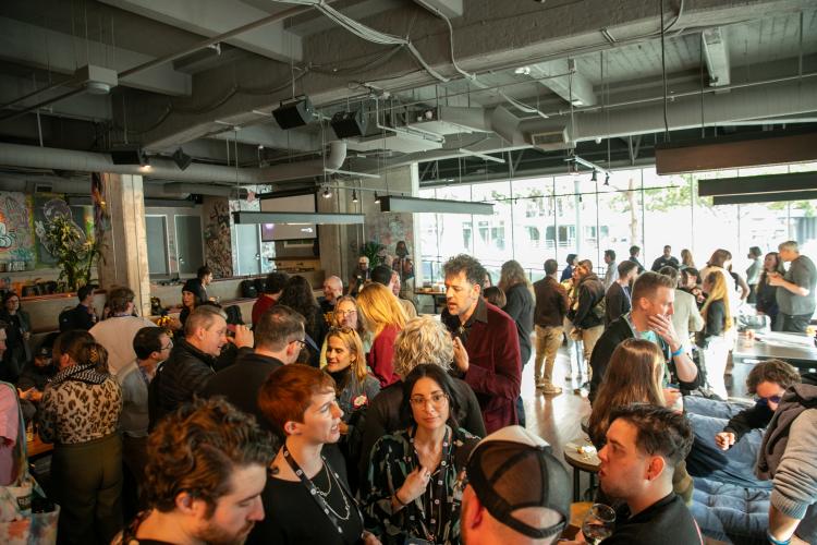 A crowd shot in a room with windows.