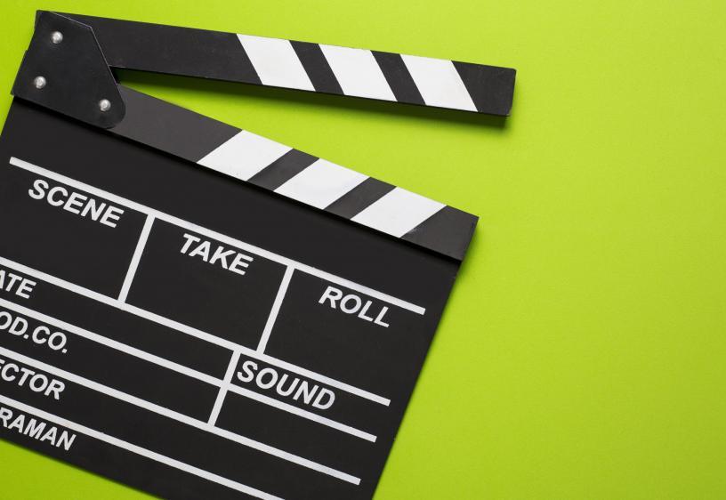 Action! A black film clapper board is over a lime green background.