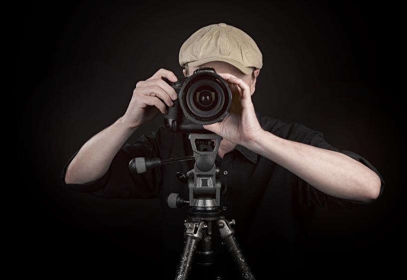 Headshot Photography and Evaluation A photographer in a cap looks into his camera to take a photo.
