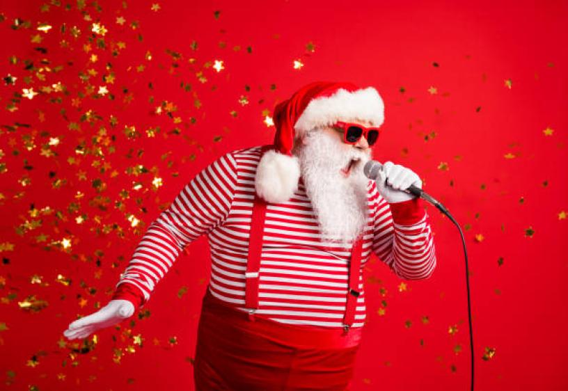 Santa Karaoke Man in white beard and red hat singing into a microphone