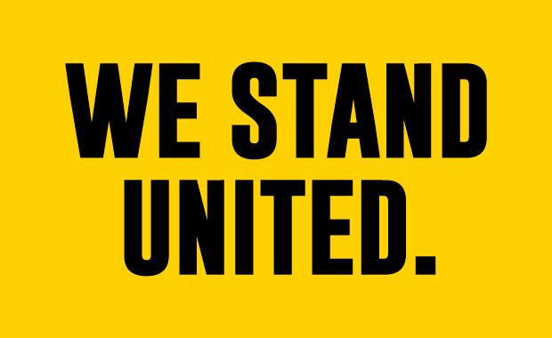"We Stand" on Line 1 in black and "United" on line 2 in black on a yellow background