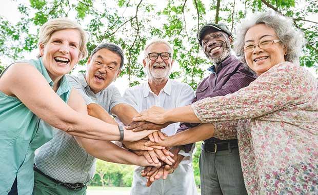 Image of seniors stacking their hands in the middle of them smiling at the camera