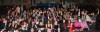 A large group of over 150 people smile for a group photo inside a movie theater.