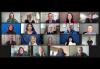 A Zoom screengrab of 19 diverse individuals. The first three rows feature five people; the last row featurs four. Each person is pictured in a specific room at home or against a home studio blue screen.