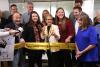 Carteris holding big scissors to cut yellow SAG-AFTRA ribbon with members all around.