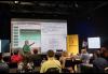 Polk stands in front of a projection screen and addresses seated members. Polk stands in front of a projection screen and addresses seated members.