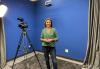 SAG-AFTRA Arizona-Utah Local member , Amanda Melby in her studio. The room is well lit with numerous stage lights and the walls are painted bright blue. To Melby's right is a camera standing on a tripod. Hero image for "Members Get Ready for Their Virtual Closeup"
