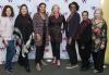 A diverse group of people stand in front of a white step-and-repeat backdrop with Women in Arts & Media Coalition written on it.