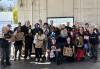 SAG-AFTRA L.A. Local members volunteer their time to help with Stamp Out Hunger at the Hollywood Post Office on May 11. People of different ethnicities inside a warehouse building. All hold a nonperishable food item; some hold paper grocery bags.