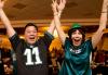 Two SAG-AFTRA members, one male and one female, wear Eagles football jerseys and smile at the party. Two SAG-AFTRA members, one male and one female, wear Eagles football jerseys and smile at the party.
