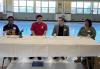 Four panelist sit at a table in a large room.