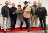 New Orleans Local President Jim Gleason, Mississippi Board member Ritchie Montgomery, National Board member Diana Boylston, Louisiana Board members Wayne Douglas Morgan and Randy Arrington and Local Vice President Billy Slaughter at the SAG Awards viewing party in New Orleans. Six people stand on a red carpet in front of a banner with the SAG-AFTRA logo on it, smiling and holding a #SagAwards sign.