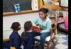 Young African-American girl sits in a rocking chair and reads to children dressed in blue and yellow. Young African-American girl sits in a rocking chair and reads to children dressed in blue and yellow.