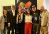 Local members and staff at the Chan National Queer Arts Center on June 24, 2024. Three men and three women stand side by side in front of a banner with the letter "F" on it. Taylor wears a suit jacket and dress shirt; the rest are dressed casually.