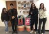 Two men and two women stand next to the two collection bins. On the wall behind them are letters that spell out "Happy Earth Day." 