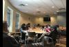 Members of the Twin Cities Local are seated around a table and conversing with one another. Members of the Twin Cities Local are seated around a table and conversing with one another.