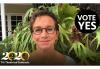 Vote Yes! Carteris in front of green foliage smiling. "VOTE YES" in white text in a black circle in the top right corner and White 2's and gold brush stroke 0's written out in 2020 with "TV?Theatrical Contracts" in white below in bottom right corner