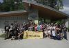 Un grupo grande y diverso afuera en un parque. Muchos visten camisetas negras de SAG-AFTRA. En la primera fila central, algunos sostienen una gran pancarta amarilla con el logotipo de SAG-AFTRA.