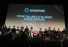 A large, diverse group stands onstage. All seen are wearing black. On the projector in the background is a title card with the SAG-AFTRA and SereiesFest logos and text, "Storyteller's Live Read 'Grave Affairs.'"