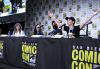 Burch, Woodward, Dalal y Elmaleh están sentados en una mesa con manteles con el logo de la Comic Con de San Diego. Elmaleh se inclina hacia adelante en su asiento con los brazos abiertos mientras los demás observan.