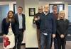 John Henning’s family gathers at the SAG-AFTRA New England Local office on March 8 to celebrate the dedication of the boardroom to Henning’s legacy and career. Six close family members of John Henning pose for a photo next to the plaque in the New England Local boardroom officially honoring his legacy, four on the right side and two on the left.