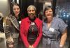 SAG-AFTRA member Megan Carroll joins Local President Andrea Lyman and executive director Jessica Maher to celebrate the work of the Labor Women’s Committee. Three diverse people smile at the camera while the rain and city lights reflect in the window behind them.