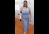 Melanie Waldman camina por la alfombra roja. Una persona con un vestido azul claro posa frente a un step-and-repeat en una alfombra roja.