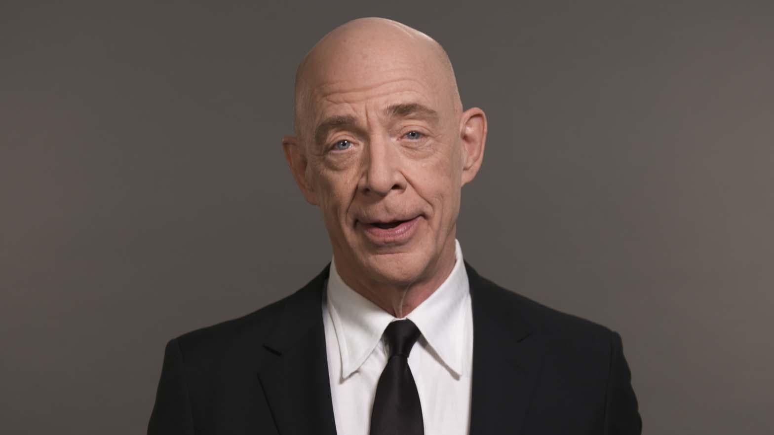 #AdsGoUnion Simmons in a black suite with a white shirt and a black tie standing in front of a grey backdrop