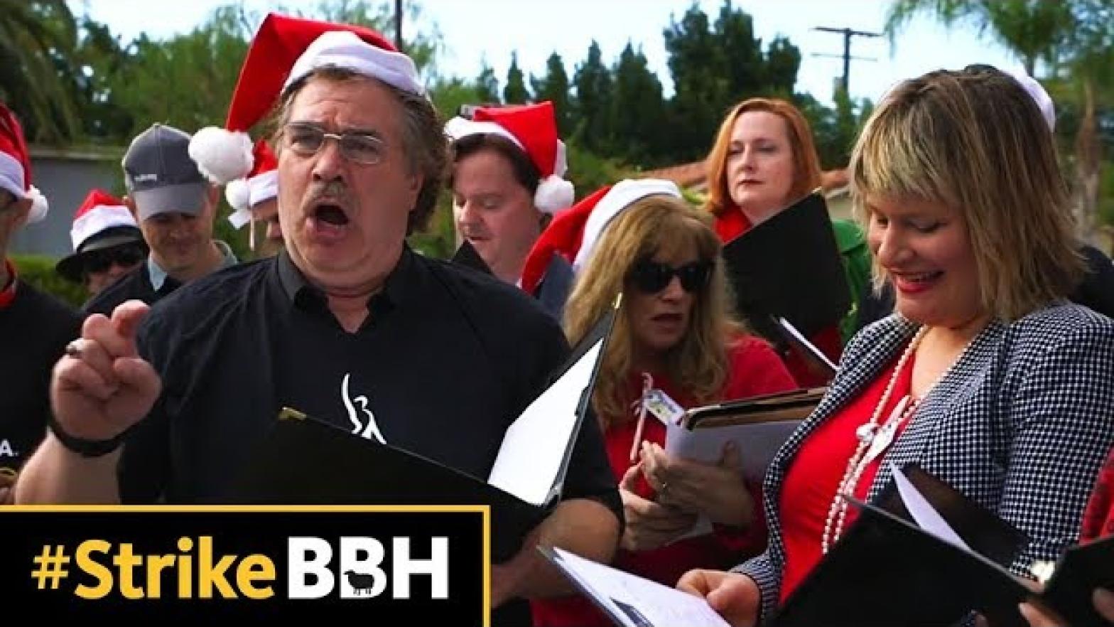 group of members holding binders in front of them wearing Santa hats
